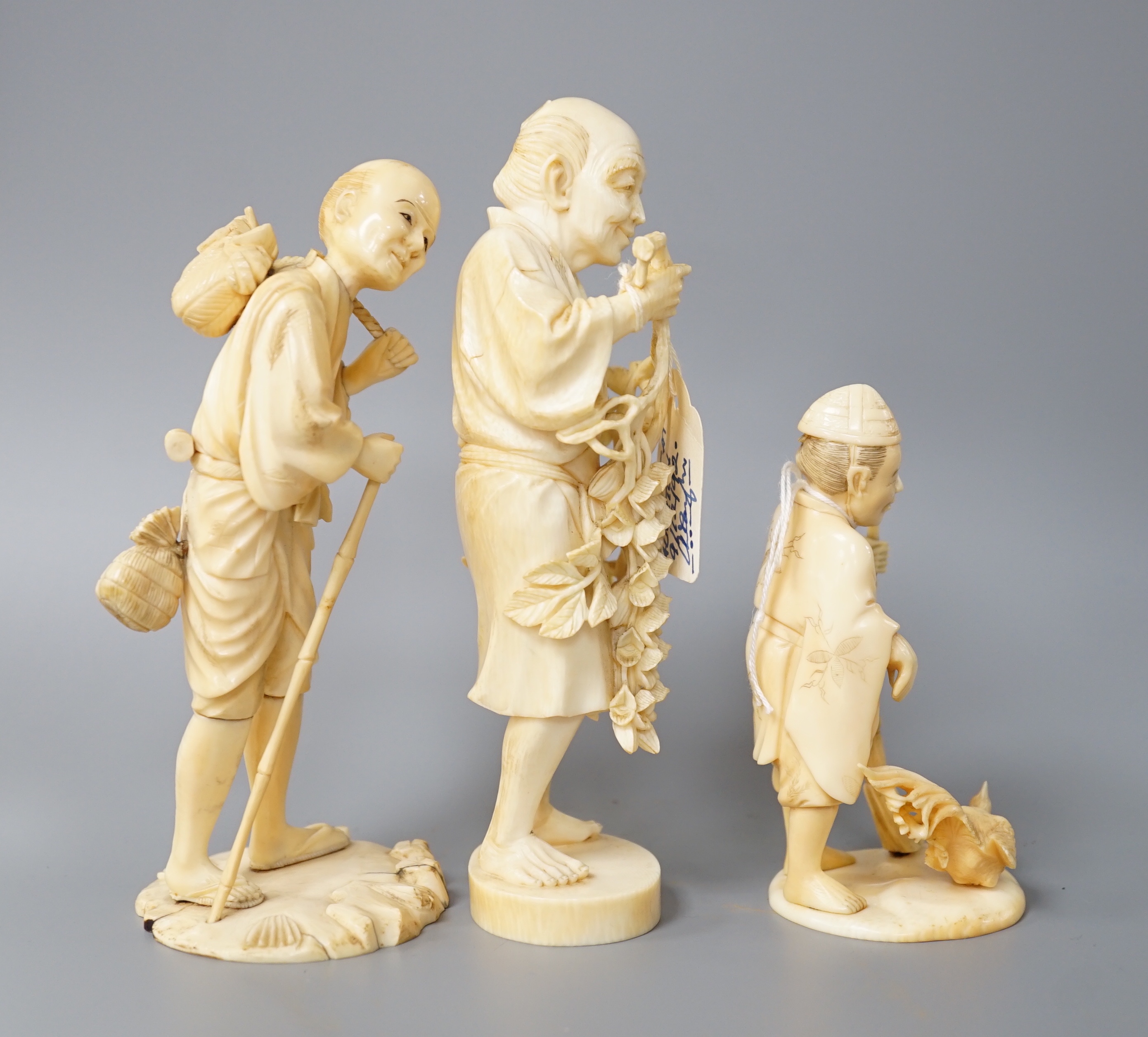 A 19th century Japanese ivory okimono of a gentleman holding a branch, another sectional figure of a gentleman with a walking stick, both signed and another 20th century okimono. Tallest 15.5cm